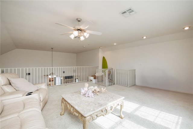 living room with ceiling fan, vaulted ceiling, light carpet, and visible vents