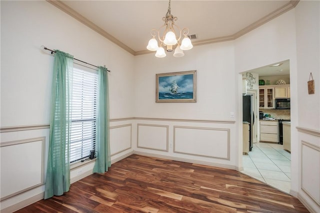 unfurnished dining area with dark wood-type flooring, a wainscoted wall, and crown molding