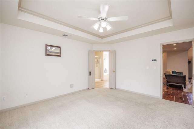 spare room featuring ornamental molding, a tray ceiling, and light carpet