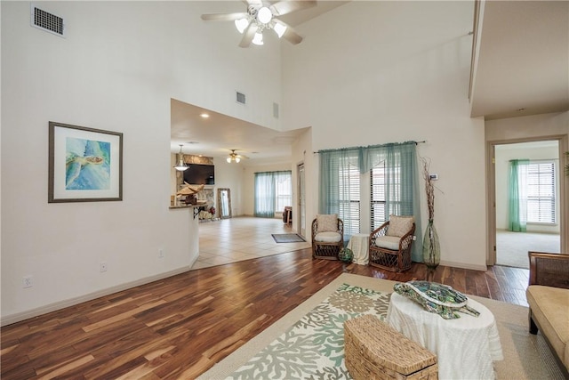 living area featuring a ceiling fan, visible vents, baseboards, and wood finished floors