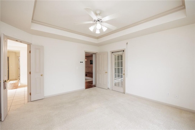 carpeted empty room featuring a raised ceiling, crown molding, and ceiling fan