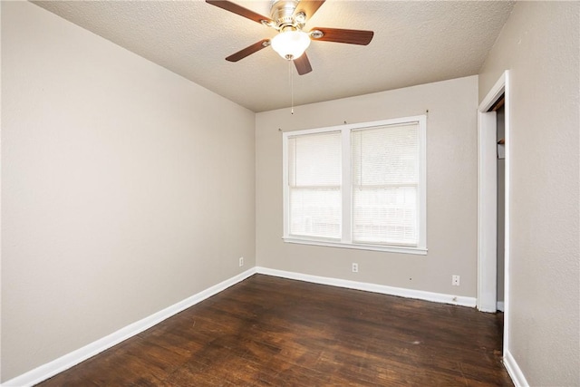 spare room with a textured ceiling, dark wood-type flooring, and baseboards