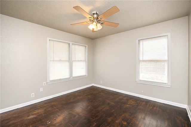 empty room featuring a textured ceiling, ceiling fan, dark wood finished floors, and baseboards