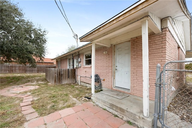 entrance to property with brick siding and fence