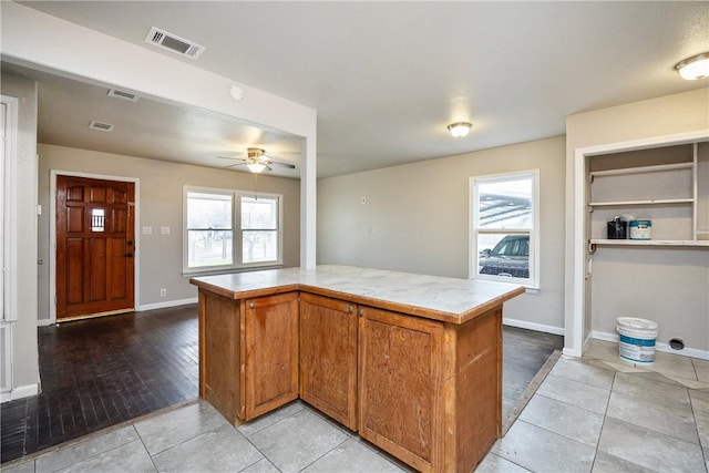 kitchen featuring a kitchen island, visible vents, brown cabinets, and light countertops