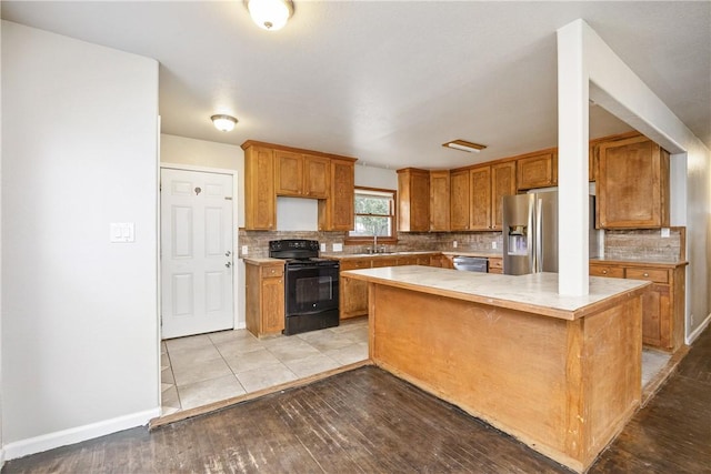 kitchen with brown cabinetry, a kitchen island, stainless steel appliances, light countertops, and a sink