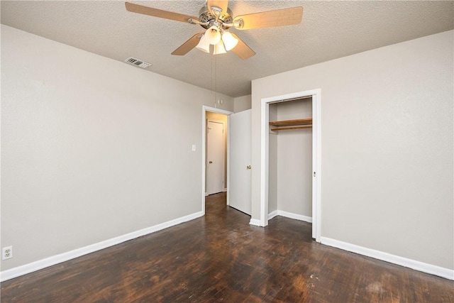 unfurnished bedroom featuring dark wood-style flooring, visible vents, a textured ceiling, and baseboards