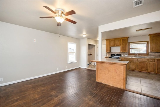 kitchen with electric range, visible vents, brown cabinets, light countertops, and a sink