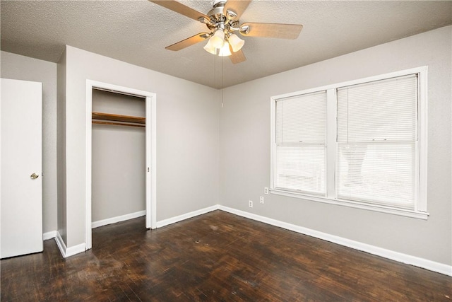 unfurnished bedroom featuring a textured ceiling, dark wood-style flooring, a ceiling fan, baseboards, and a closet