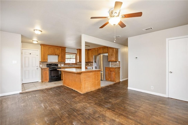 kitchen with stainless steel fridge with ice dispenser, brown cabinets, black range with electric stovetop, a center island, and light countertops