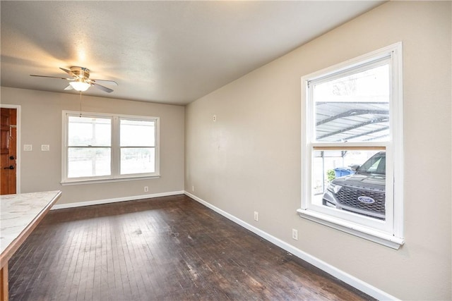 unfurnished living room featuring baseboards, ceiling fan, dark wood finished floors, and a healthy amount of sunlight