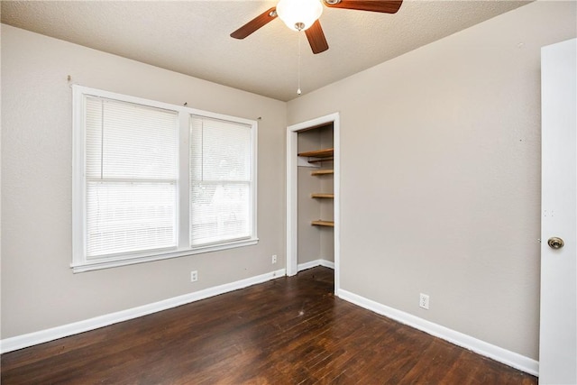 empty room featuring dark wood-type flooring, baseboards, and a ceiling fan