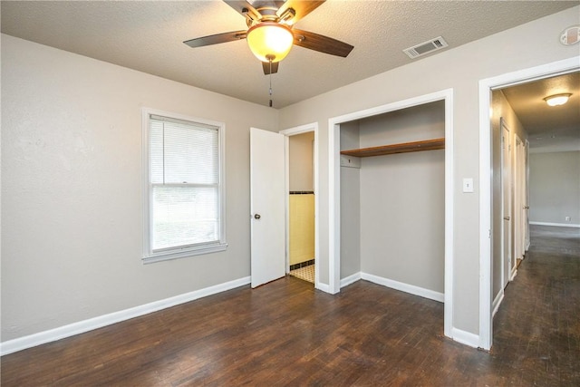 unfurnished bedroom featuring baseboards, a closet, visible vents, and dark wood-type flooring