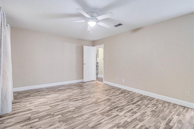 spare room featuring visible vents, baseboards, light wood-type flooring, and a ceiling fan