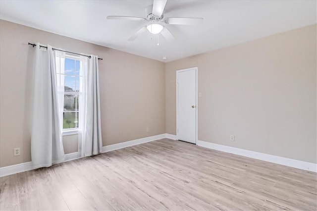 spare room with ceiling fan, light wood-type flooring, and baseboards