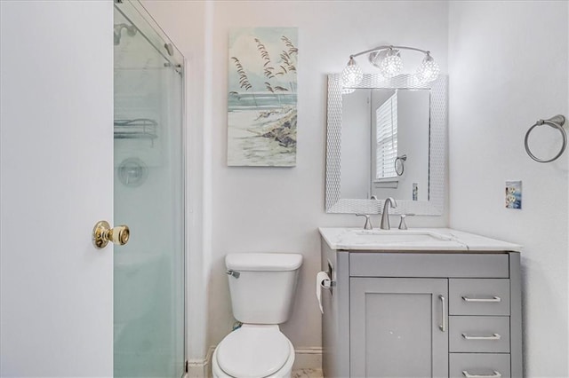 bathroom featuring a shower with shower door, baseboards, toilet, and vanity