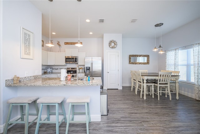 kitchen featuring stainless steel appliances, hanging light fixtures, white cabinets, and kitchen peninsula