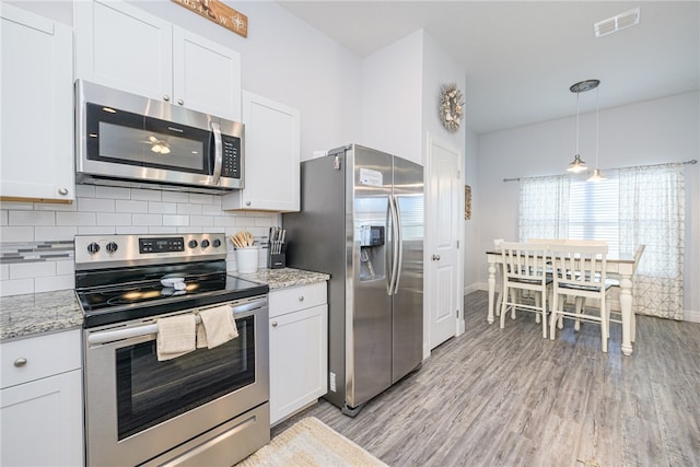 kitchen with white cabinetry, light stone countertops, appliances with stainless steel finishes, and light hardwood / wood-style flooring