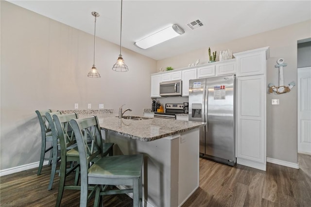 kitchen with appliances with stainless steel finishes, decorative light fixtures, white cabinetry, sink, and kitchen peninsula