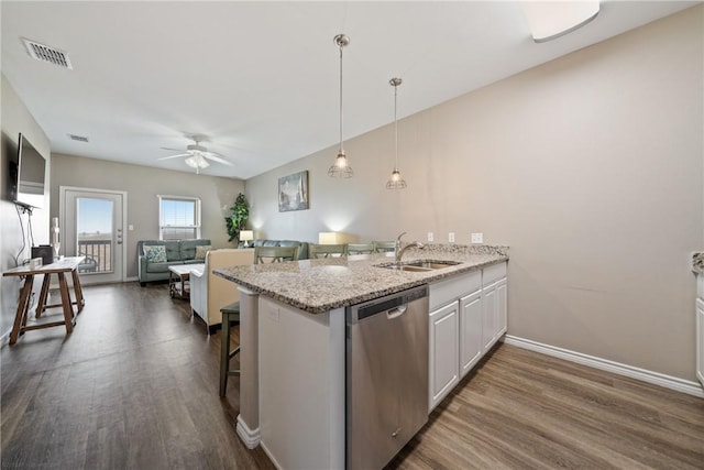 kitchen featuring white cabinetry, sink, a breakfast bar area, stainless steel dishwasher, and light stone counters