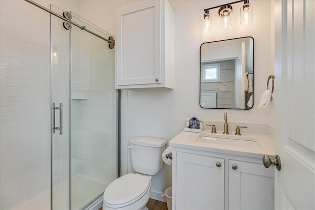 bathroom featuring vanity, a shower with shower door, and toilet