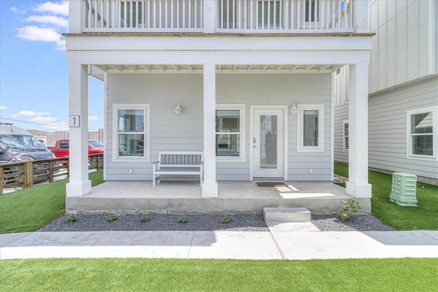 doorway to property featuring a lawn, a porch, and a balcony