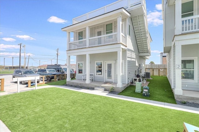 view of front facade featuring a balcony, central air condition unit, and a front lawn