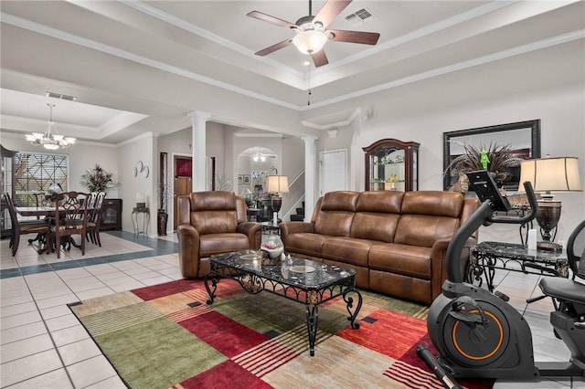 living area featuring a tray ceiling, decorative columns, visible vents, light tile patterned flooring, and ceiling fan with notable chandelier