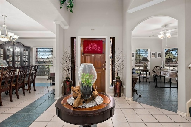 entrance foyer with light tile patterned floors, plenty of natural light, crown molding, and ceiling fan with notable chandelier