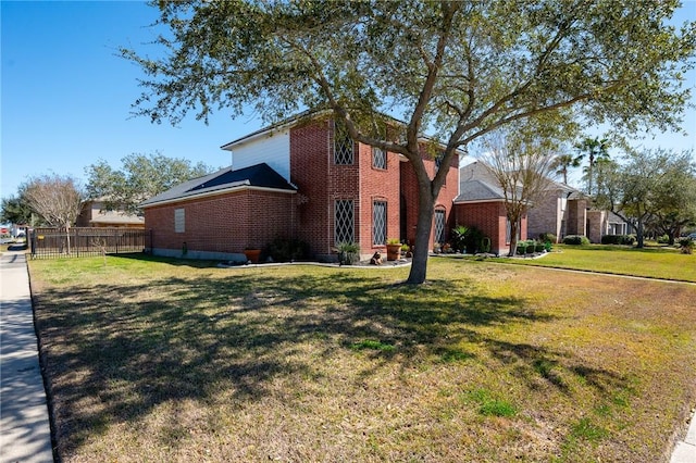 view of property exterior featuring a yard, brick siding, and fence