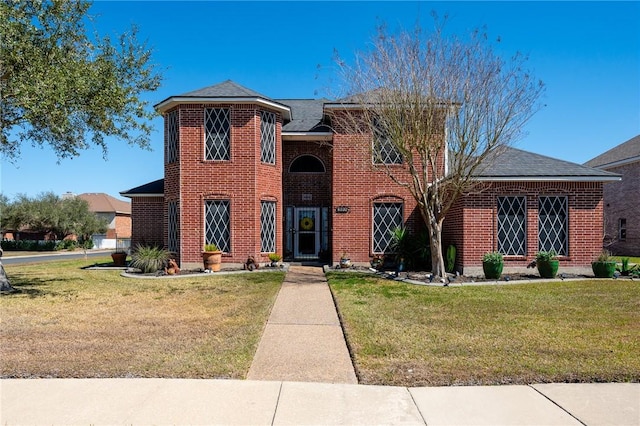 traditional-style home featuring a front lawn and brick siding