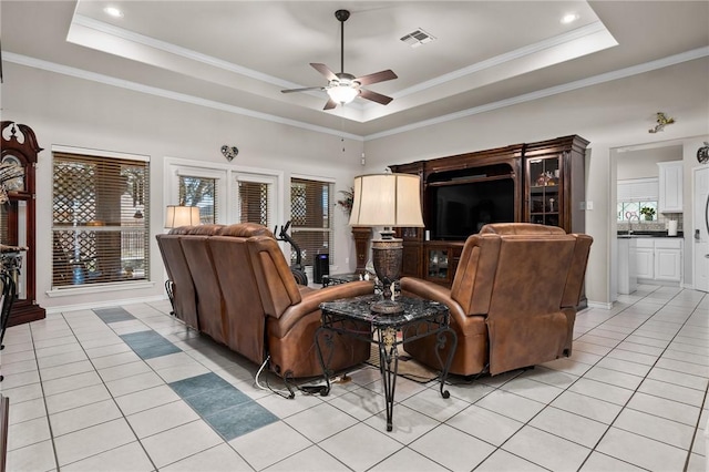 living room with visible vents, a tray ceiling, ornamental molding, and light tile patterned flooring