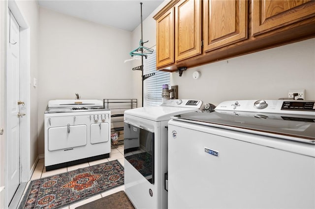 laundry room featuring light tile patterned floors, separate washer and dryer, and cabinet space