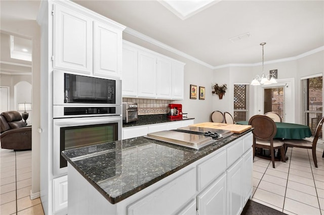 kitchen with ornamental molding, black microwave, oven, and white cabinets