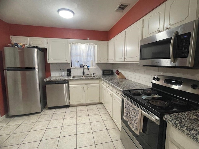 kitchen featuring stainless steel appliances, sink, tasteful backsplash, light tile patterned flooring, and white cabinetry