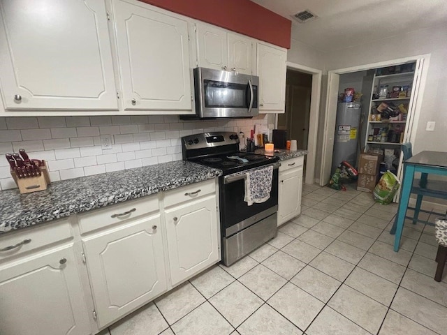 kitchen featuring tasteful backsplash, appliances with stainless steel finishes, light tile patterned floors, and white cabinets