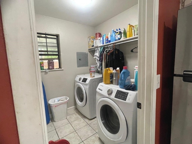 clothes washing area featuring electric panel, light tile patterned floors, and washer and clothes dryer