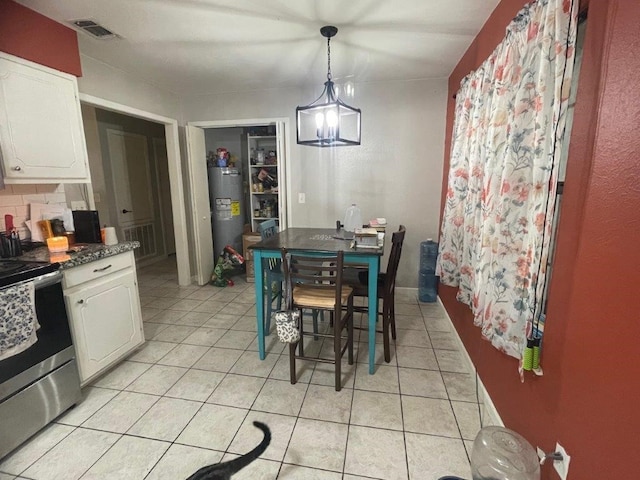 tiled dining area featuring water heater and an inviting chandelier