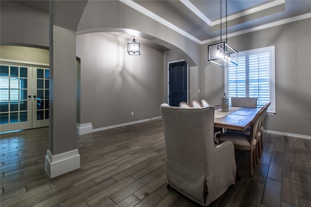 dining room featuring dark wood-type flooring, ornamental molding, a tray ceiling, and french doors