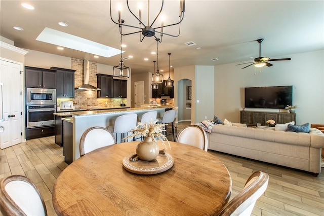 dining room featuring ceiling fan, light wood-type flooring, and a skylight