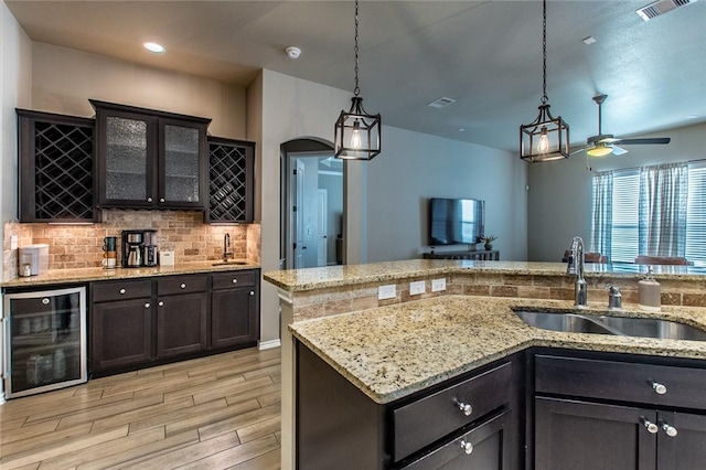 kitchen featuring wine cooler, decorative light fixtures, sink, and decorative backsplash