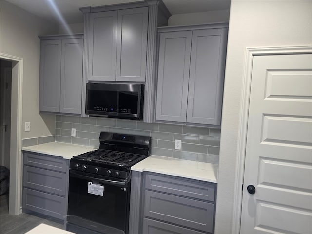 714 Mereet Dr, Corpus Christi, TX 78418 - kitchen with gray cabinets, black range with gas cooktop, stainless steel microwave, and backsplash