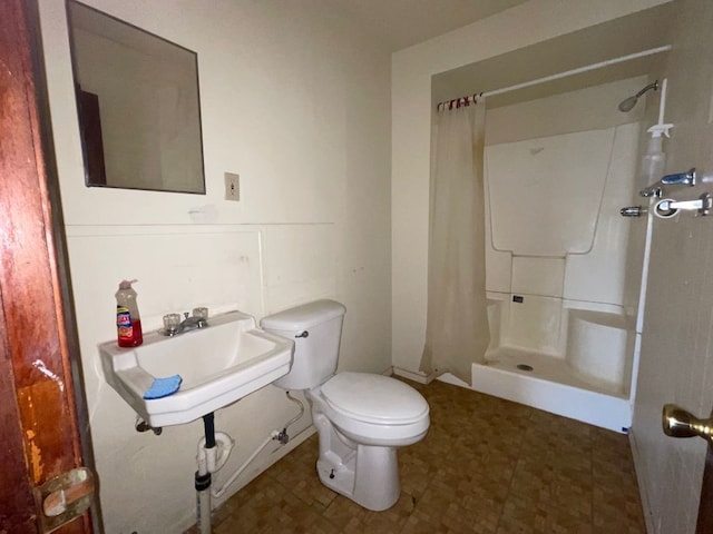 bathroom featuring walk in shower, sink, and toilet