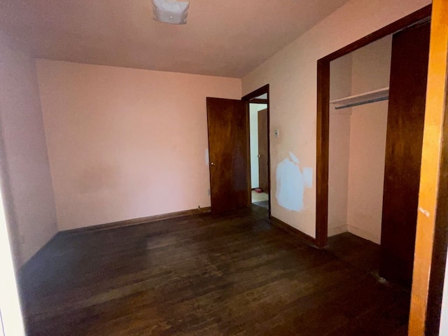 unfurnished bedroom with a closet and dark hardwood / wood-style flooring