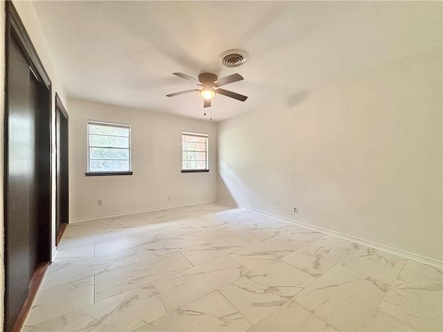spare room featuring a ceiling fan, baseboards, visible vents, and marble finish floor