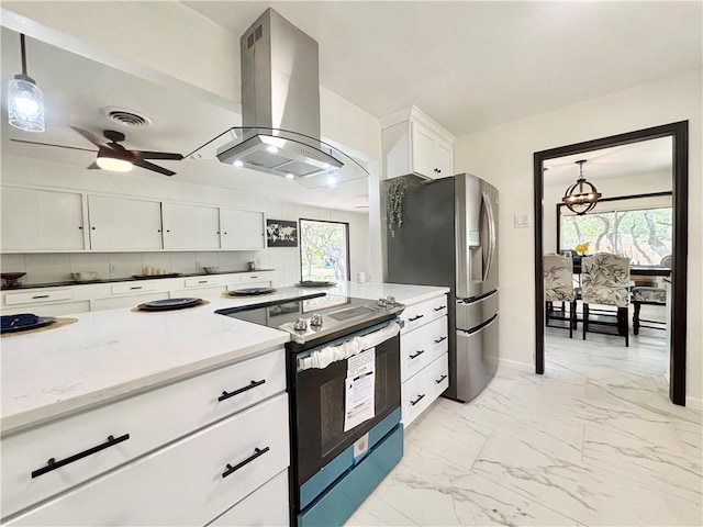 kitchen with island exhaust hood, appliances with stainless steel finishes, white cabinets, ceiling fan with notable chandelier, and marble finish floor