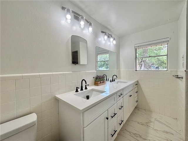 2551 Henrietta Pl, Ingleside, TX 78362 - bathroom featuring tile walls, marble finish flooring, toilet, a wainscoted wall, and double vanity