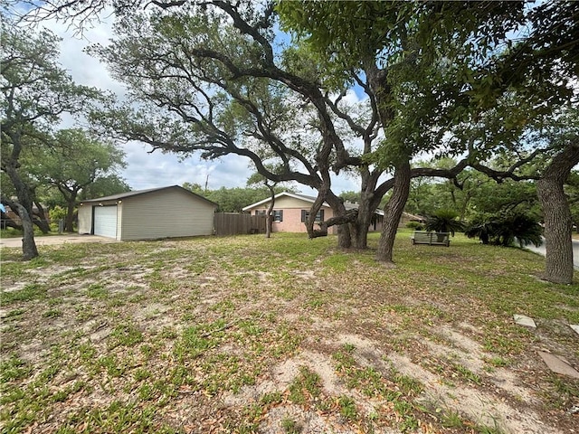 view of yard featuring fence, a detached garage, and an outdoor structure