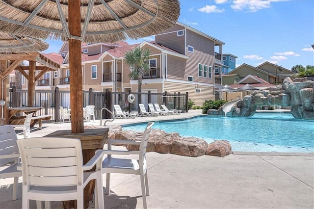 pool featuring a water slide, fence, a gazebo, and a patio