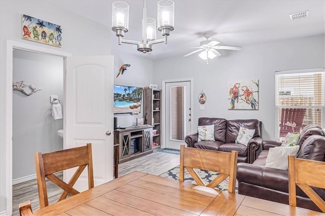 living area with ceiling fan with notable chandelier, wood finished floors, and visible vents